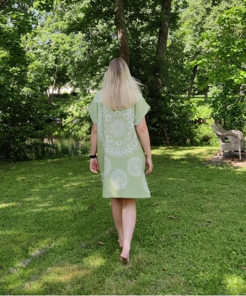 Nainen kävelee vihreä tunika päällä ulkona nurmikolla